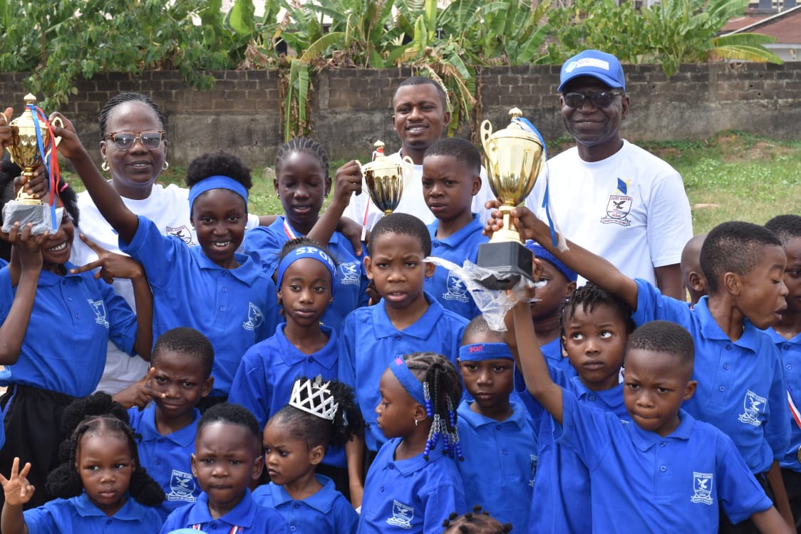 Pupils and staff holding up trophies after sports day